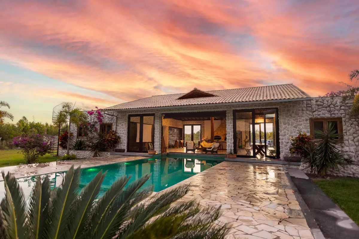 Stone-clad property with a pool photographed at sunset for a listing
